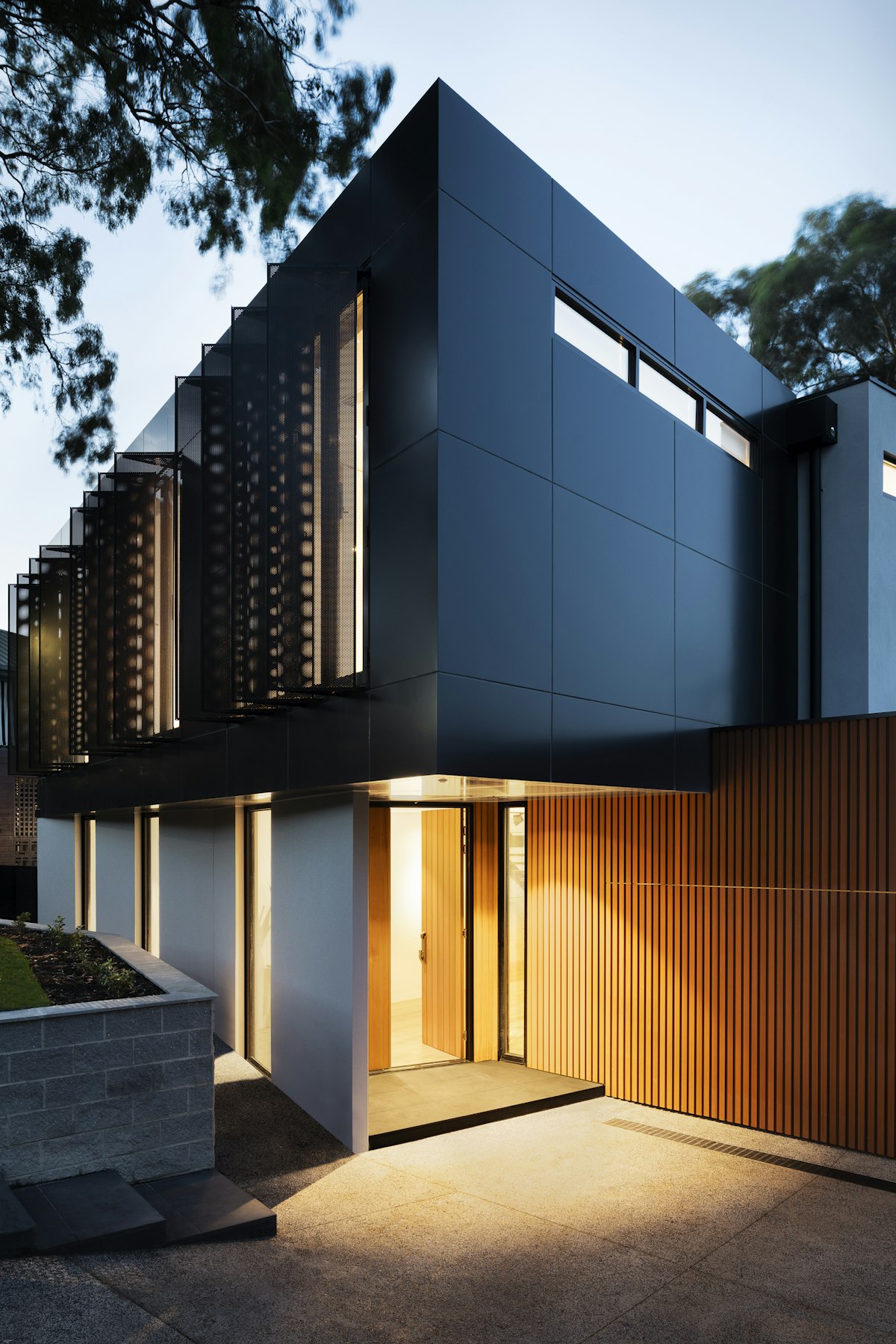 Contemporary home facade in dark cladding and timber at dusk